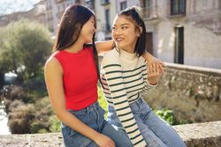 Happy female friends sitting outside on sunny day