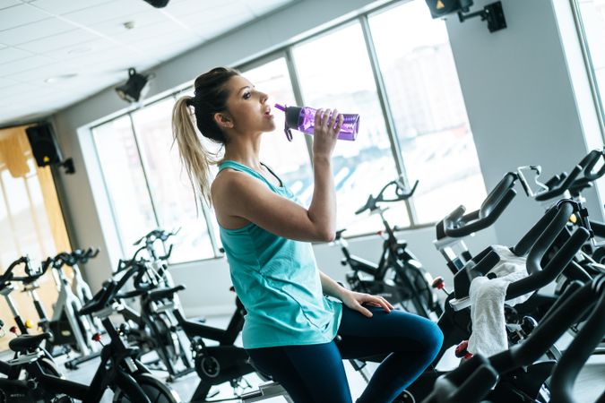 Woman drinking water on exercise machine