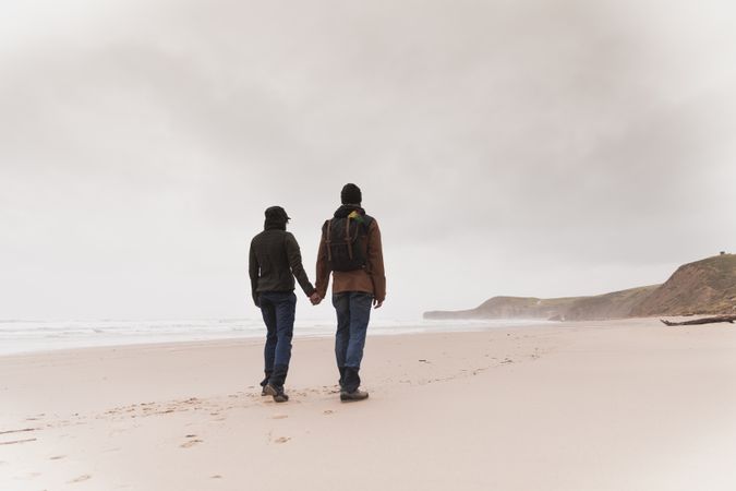 Couple walking on sand shore near water