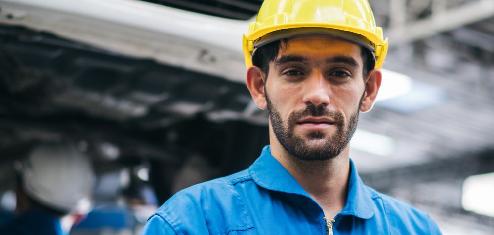 Male mechanic in shop wearing yellow hard hat