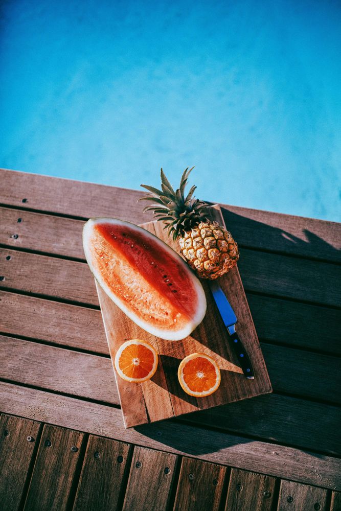 Fruit platter on a wooden board by the pool on a sunny day