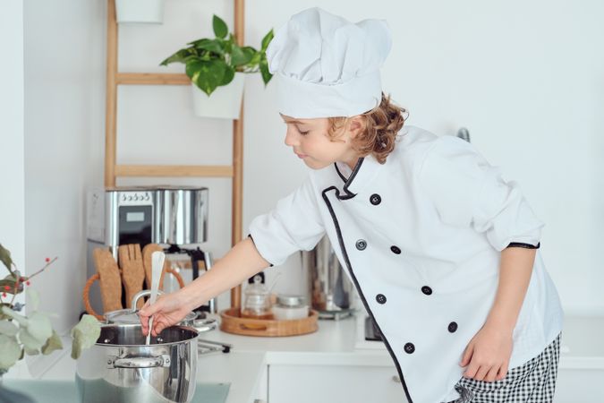 Content boy cooking with pan on stove