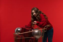 Young girl in red sweater reaches into gold shopping cart