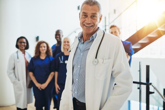 Smiling doctor in lab coat with medical staff