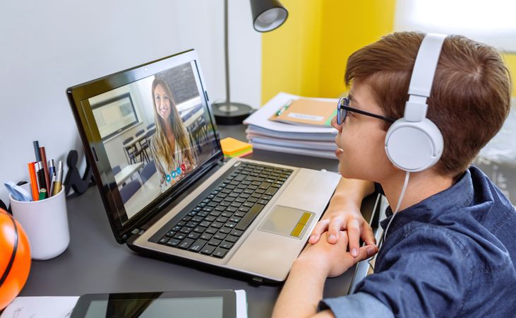 Boy with headphones receiving class at home with laptop from his bedroom