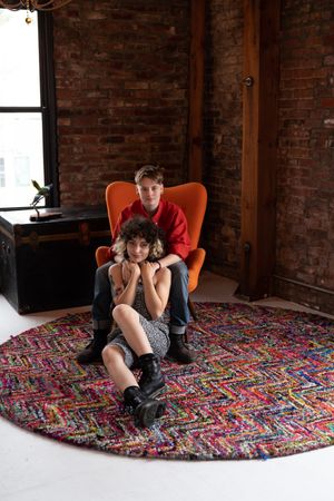 Young woman sits in chair with her partner sitting on floor in front