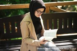 Woman reading while sitting on a park bench 5lkMa0
