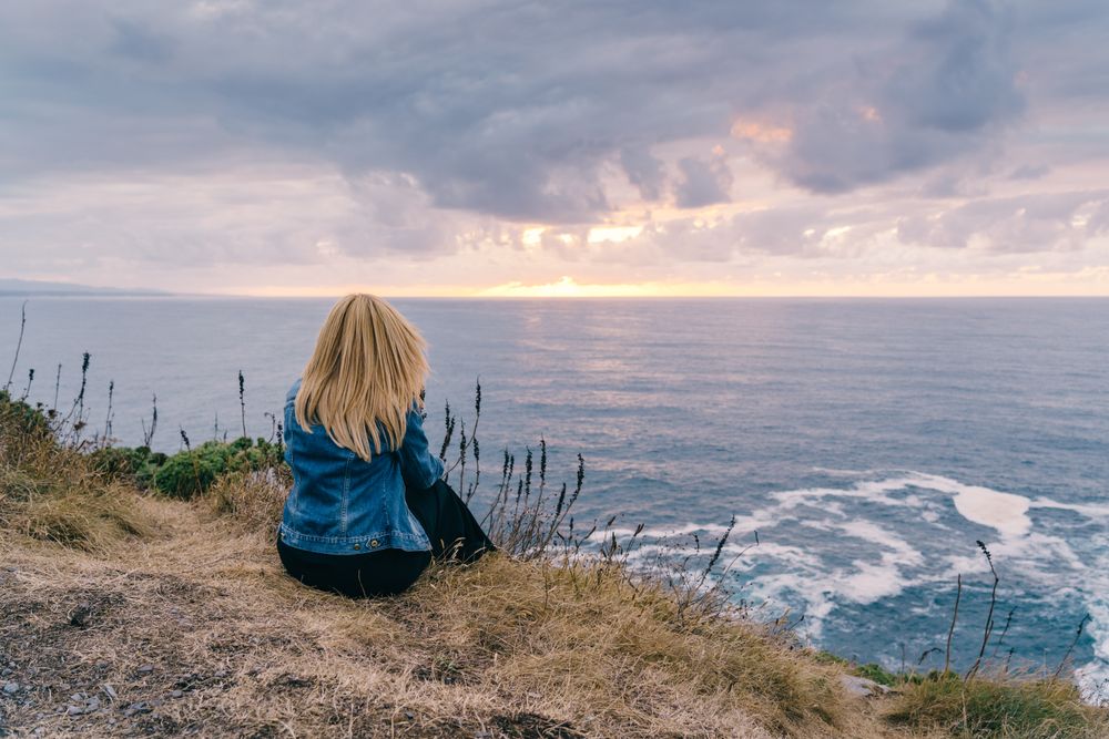 Woman on seashore against dusky clouds