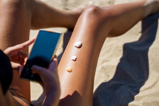 Enjoy a Relaxing Day at the Beach Sunbathing while applying Sunscreen and using my Smartphone