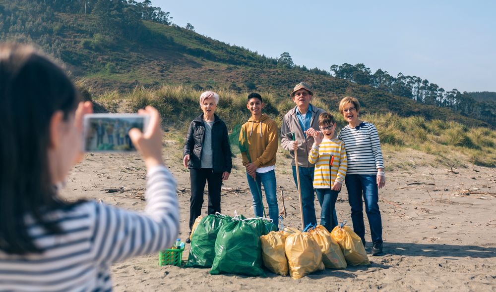 Girl taking photo to group of volunteers after cleaning beach