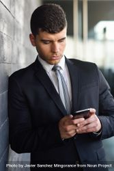 Portrait of man with blue eyes in suit and tie checking phone beQx6b