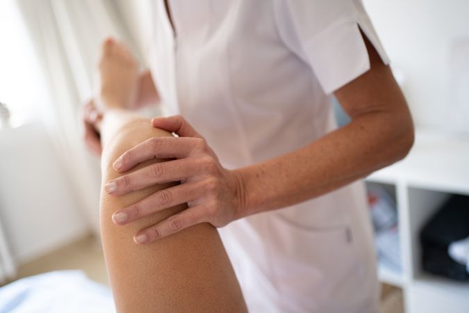 Close up of osteopath holding knee of patient