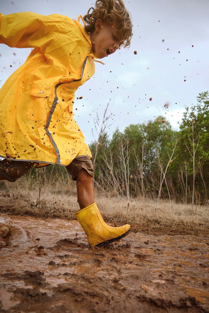Preteen boy playing in mud in nature