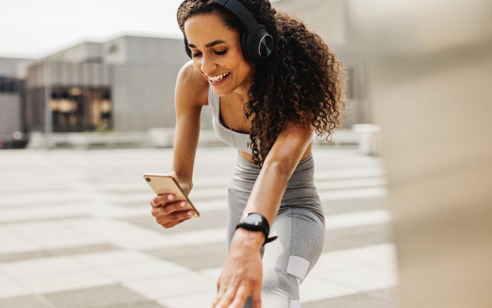 Smiling woman doing stretching workout and using smart phone