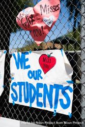Two colorful signs taped to a school fence from teachers to students 0JG1r5