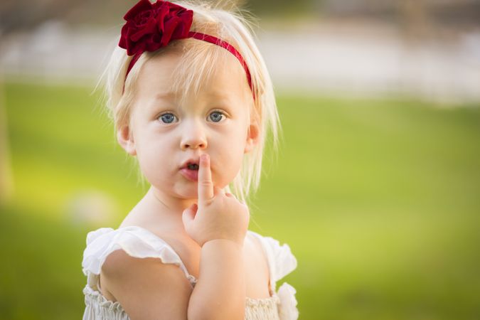Adorable Little Girl Wearing White Dress In A Grass Field