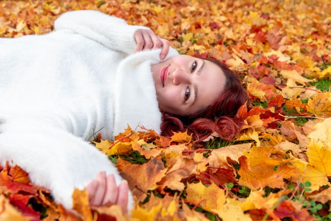 Woman lying in autumn leaves looking at camera