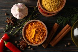 Wooden table scattered with spices and ingredients for cooking, close up