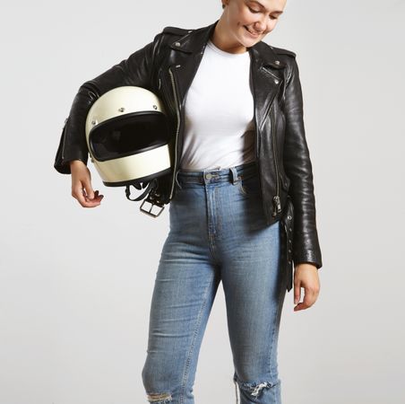 Smiling woman in dark leather jacket with light t-shirt posing with motorcycle helmet