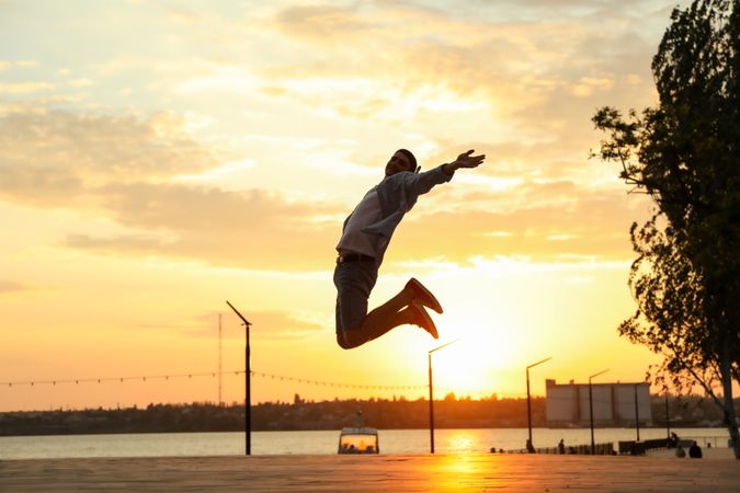 Photo of a young man in a jump. Happy man. Amazing sunset