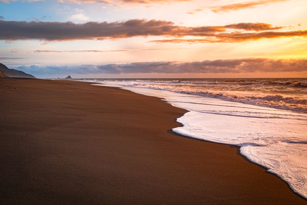 Frothy waves coming in on a quiet beach at sunset