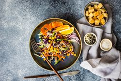 Top view of healthy vegetable salad and lemon slices in bowl on counter with copy space