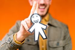 Smiling man holding funny paper toy