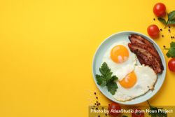 Looking down at plate of breakfast with eggs, sunny side up with bacon, copy space 4NXVD0