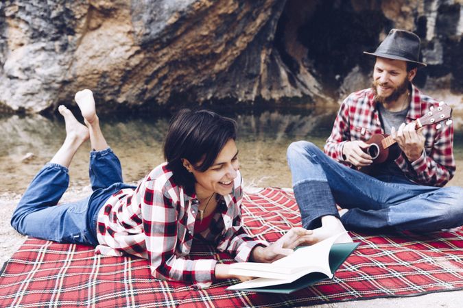 Chilling couple with book and guitar on shore