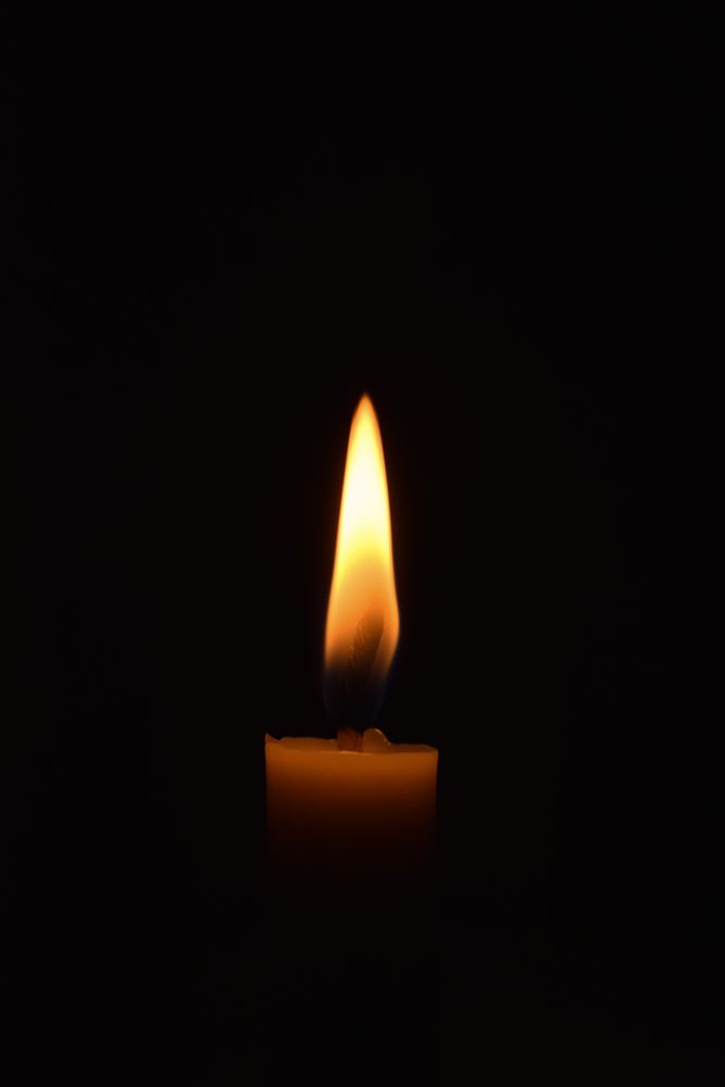 Side view of candle burning in the dark with copy space
