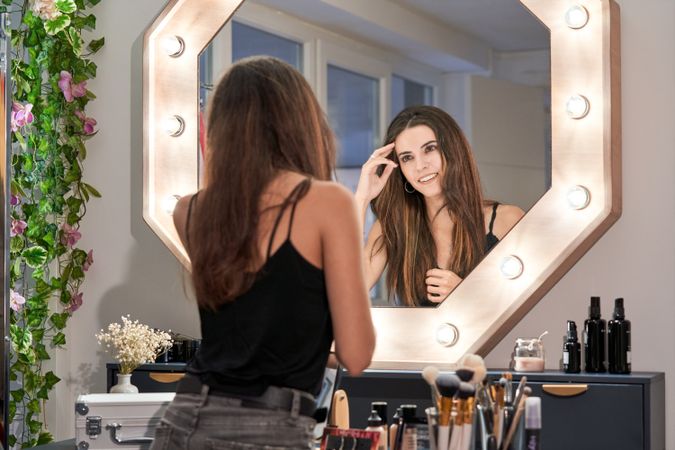 Brunette woman looking in makeup mirror
