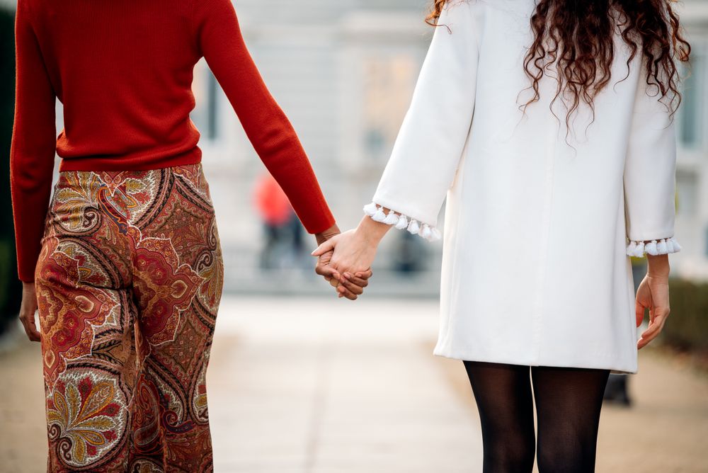 Two interracial women holding hands walking in the streets