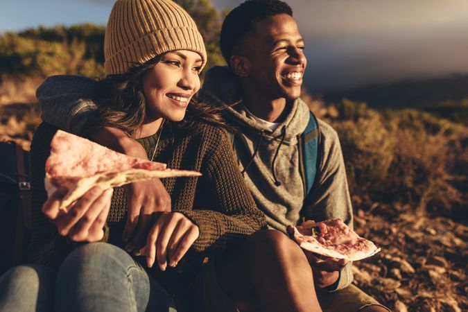 Couple on hiking trip eating pizza and admiring the view