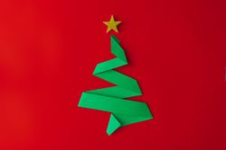 Minimal origami style folded paper Christmas tree on red background