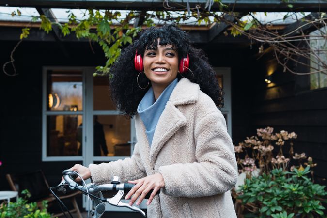 Cheerful Black woman in headphones with bicycle