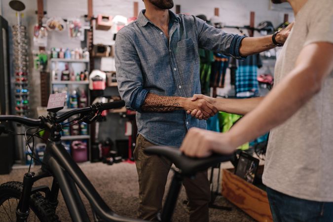 Man with tattoos shaking hands in a bike shop