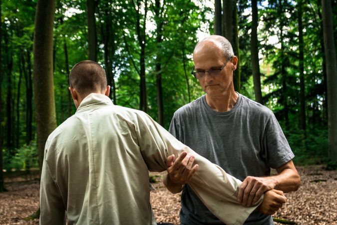 Two men training martial arts in forest