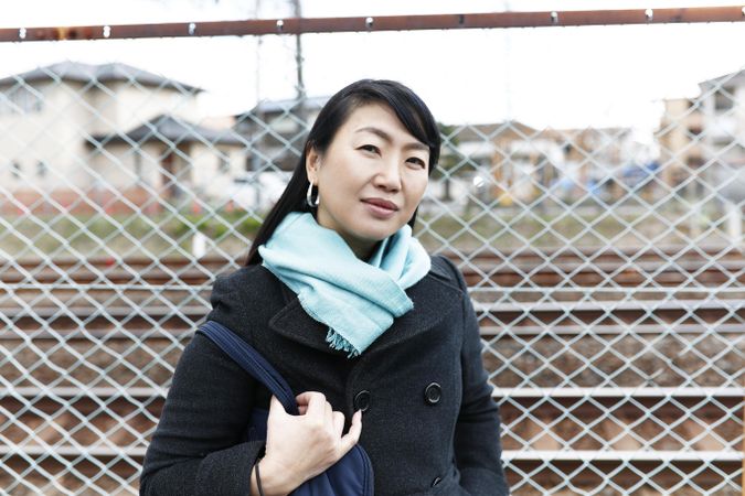 Portrait of east Asian woman standing beside fence outdoor