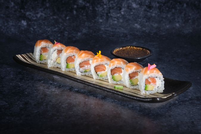 Sushi rolls covered with fresh salmon served on plate