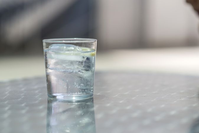 Glass of water with ice on a silver table outdoors