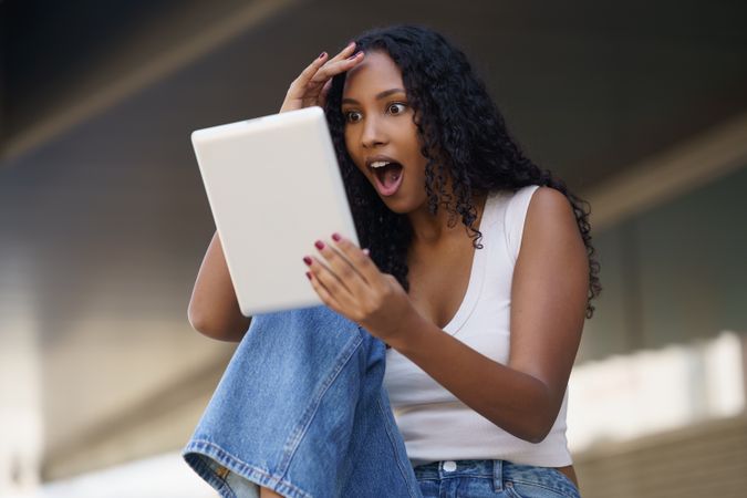A Young Woman, Filled with Surprise, Excitedly Discovers Exciting News on Her Tablet Device