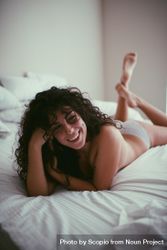 Woman with curly hair lying on bed 0VLoX4