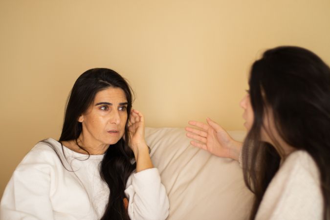 Mother and daughter discussing sitting on a sofa