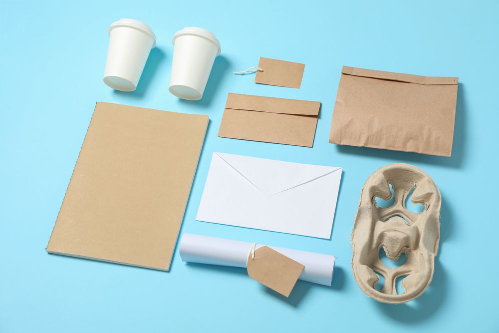 Composition with paper cups and office supplies on blue background, copy space