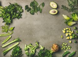 Arrangement of sliced green garden vegetables on concrete surface, copy space