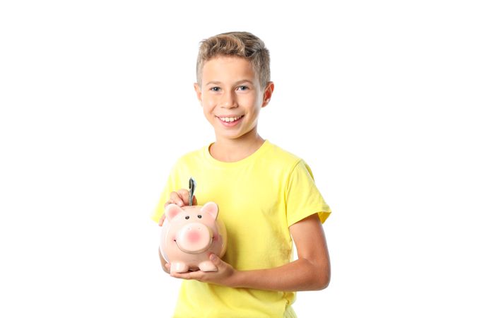 Boy in yellow t-shirt with piggy bank isolated on blank background