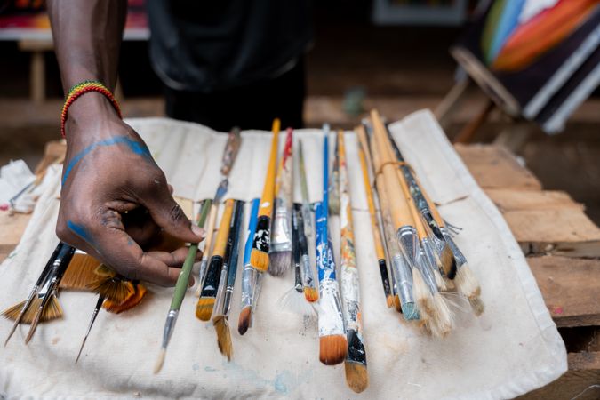 Black artist choosing among a collection of paint brushes