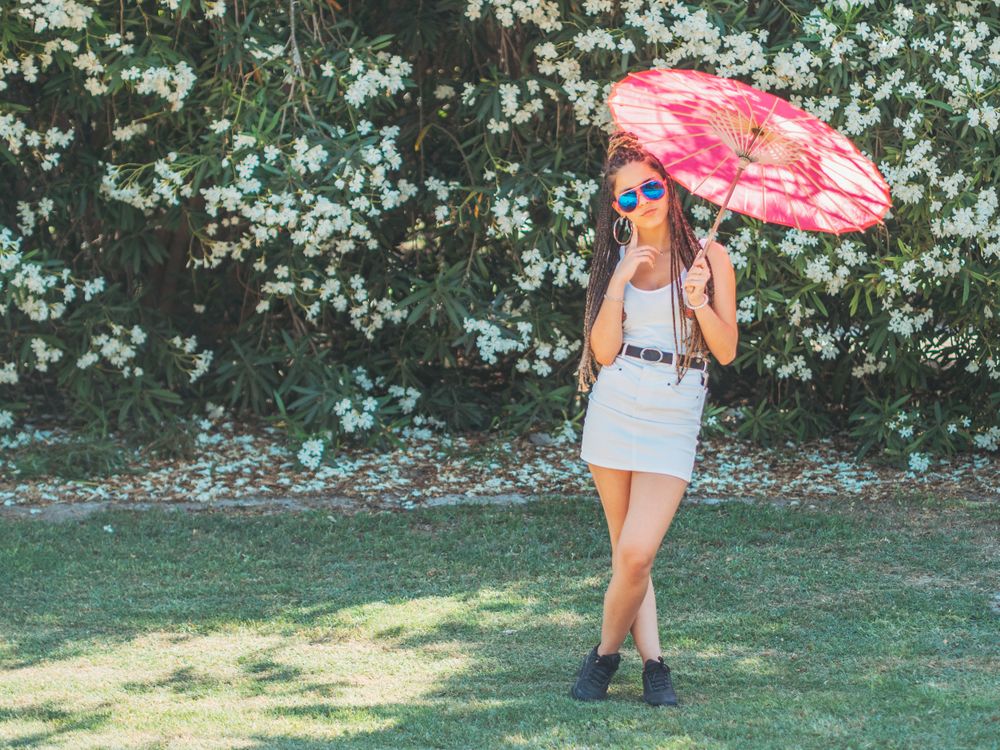 Fit young female with umbrella standing near blooming trees
