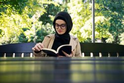 Woman reading a novel at a park table on a sunny day