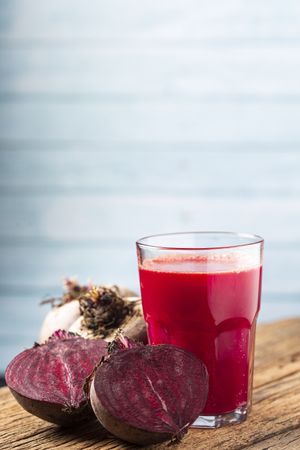 Red beet juice in a glass cup on the wooden table.
